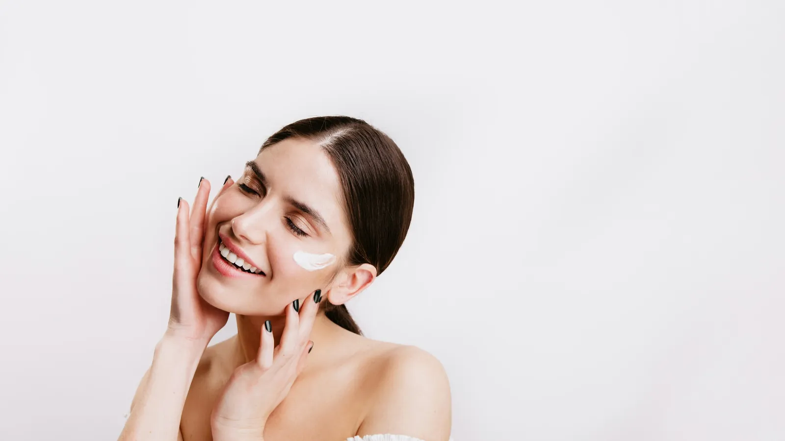 Smiling woman touching her cheek after skincare, linking to the Cosmetiq Medicine before and after gallery