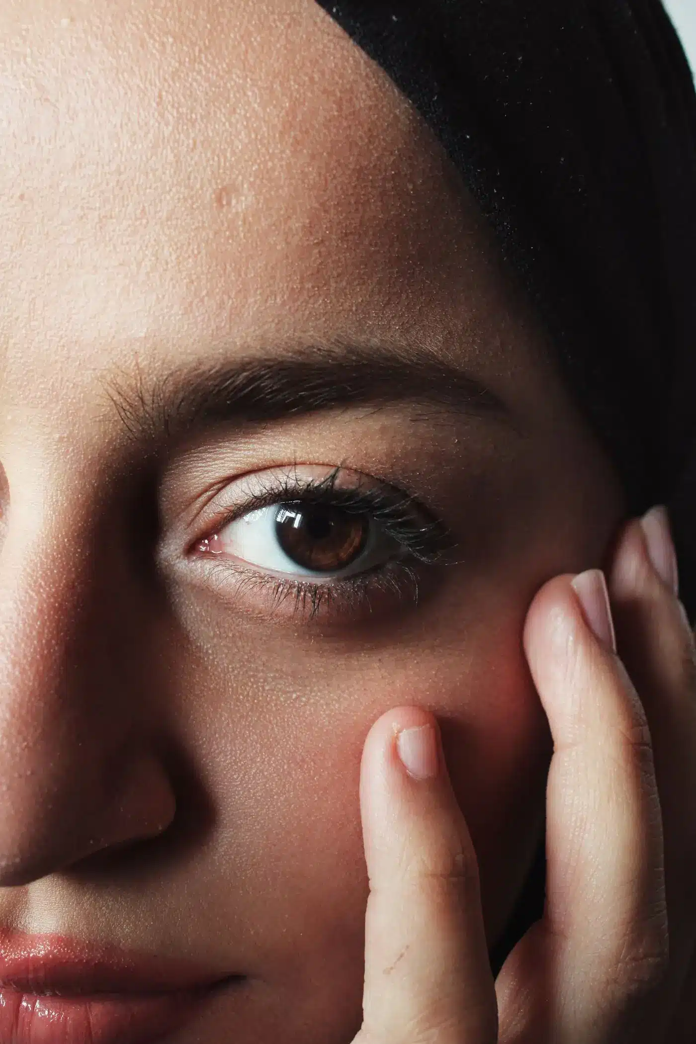 Close view of skin texture on the cheek, with a hand resting on the face
