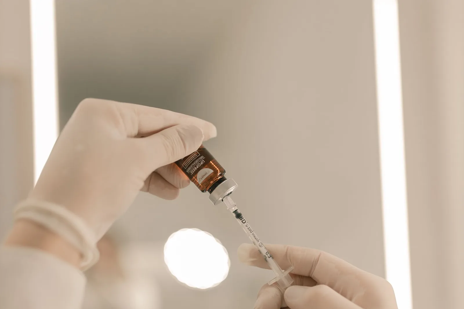 Gloved aesthetic professional drawing medication from a labeled vial before an injectable treatment, illustrating medical oversight standards for med spa care in Portland, OR and Vancouver, WA